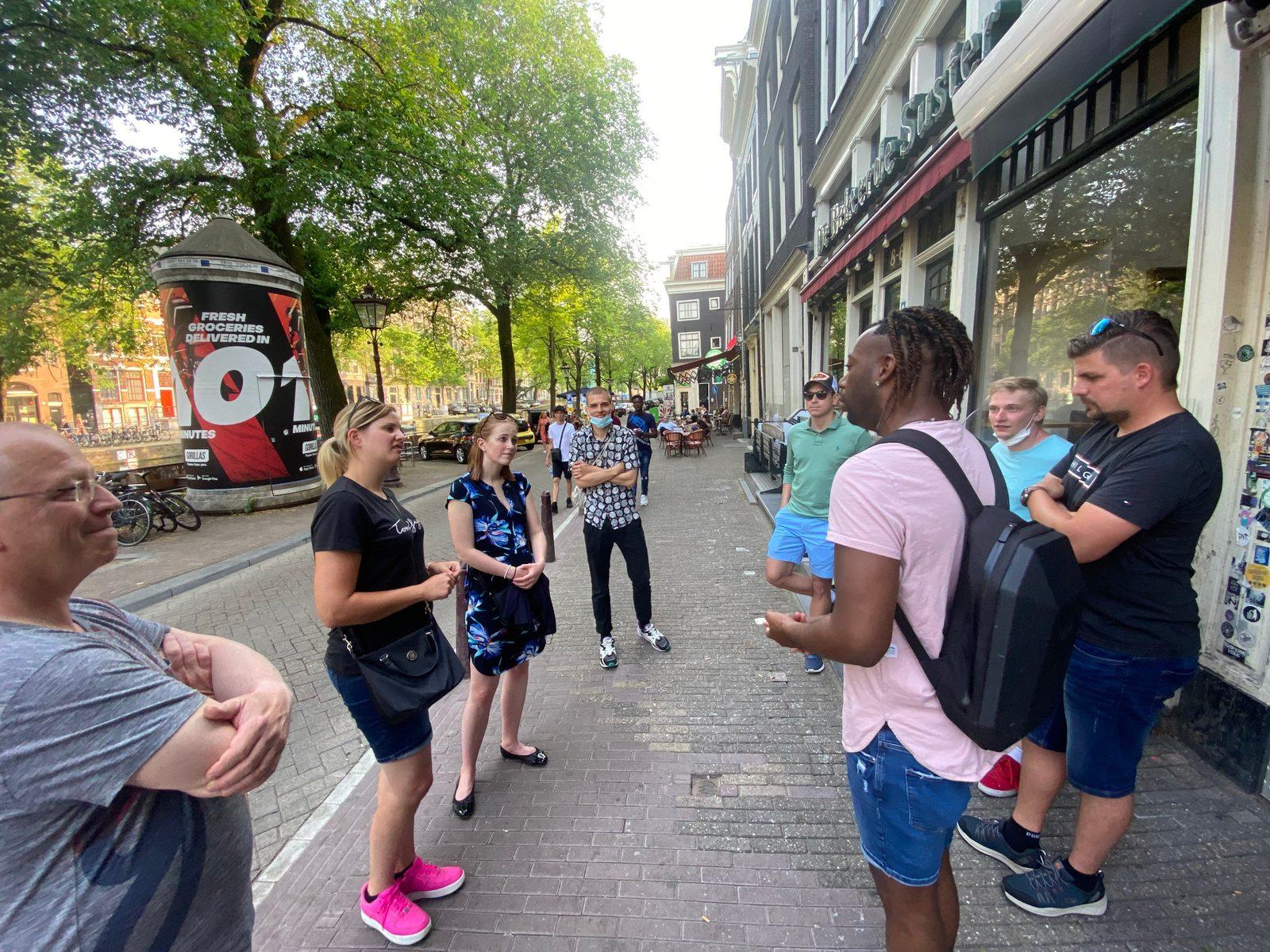 Privater Gastgeber mit einer kleinen Gruppe in einer Amsterdamer Straße während eines Concierge-Tages