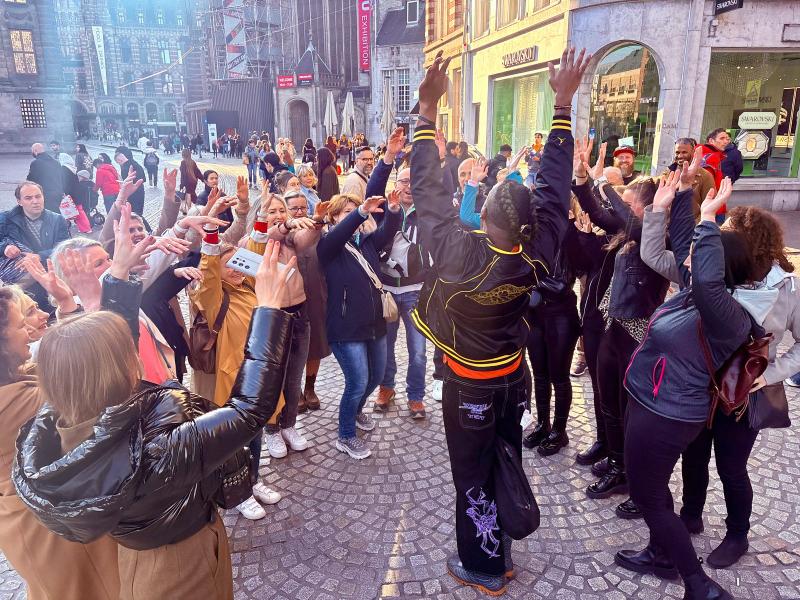 Lebhafte Menschenmenge auf dem Amsterdamer Kopfsteinpflaster während eines Tourerlebnisses