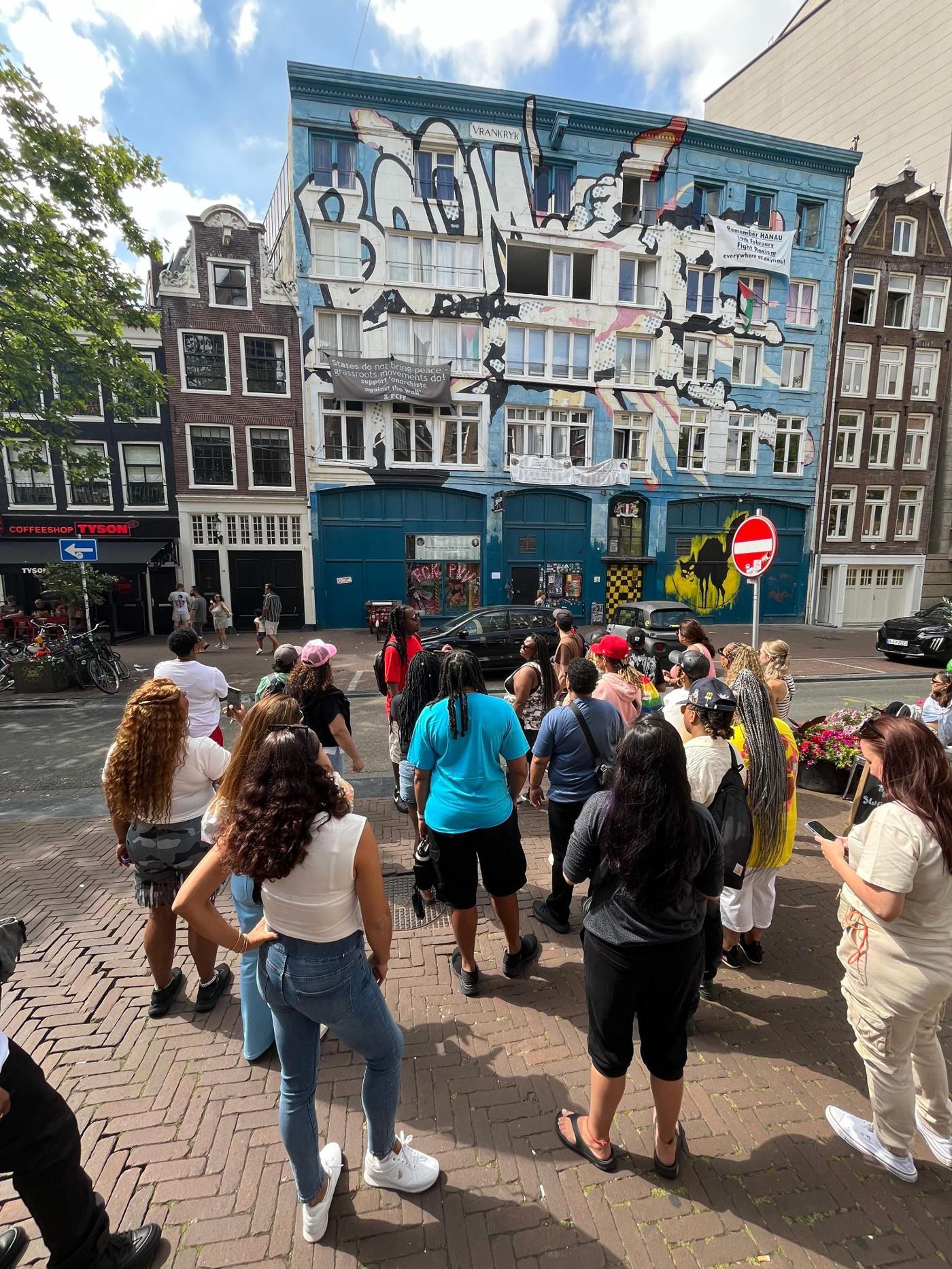 Tour group on the Spuistraat facing a row of gabled brick houses in Amsterdam's historic centre